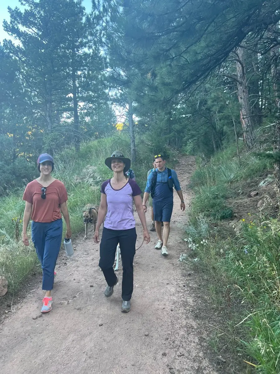 Three Forum members walking a wooded Colorado trail with a dog on a leash.