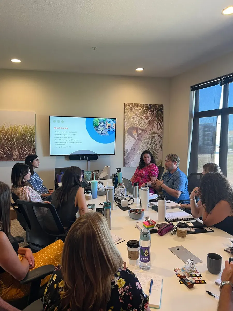Forum members around a conference table during a supplier presentation, with a slide introducing an organic ingredient supplier on screen.